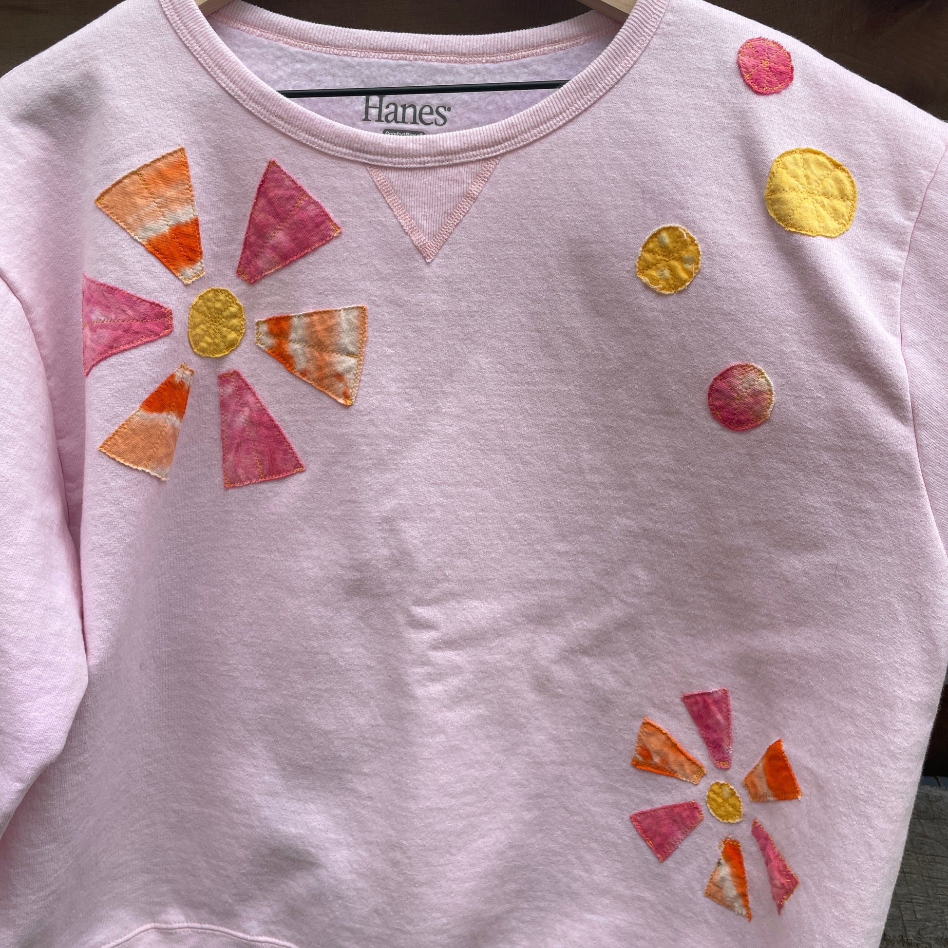A light pink sweatshirt with applique orange and pink flowers