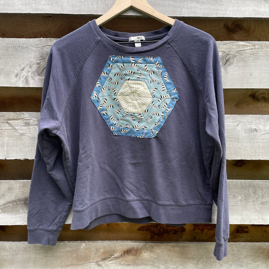 A faded navy blue sweatshirt with a blue hexagonal quilt square appliqué on the front