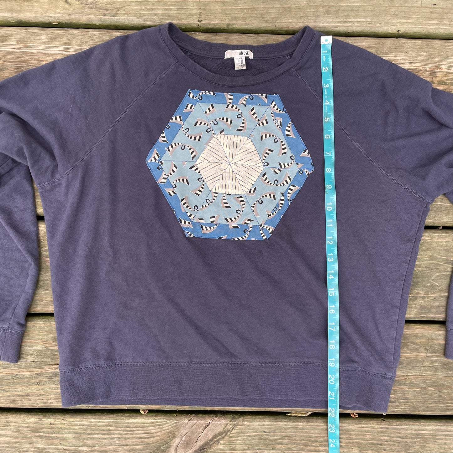A faded navy blue sweatshirt with a blue hexagonal quilt square appliqué on the front