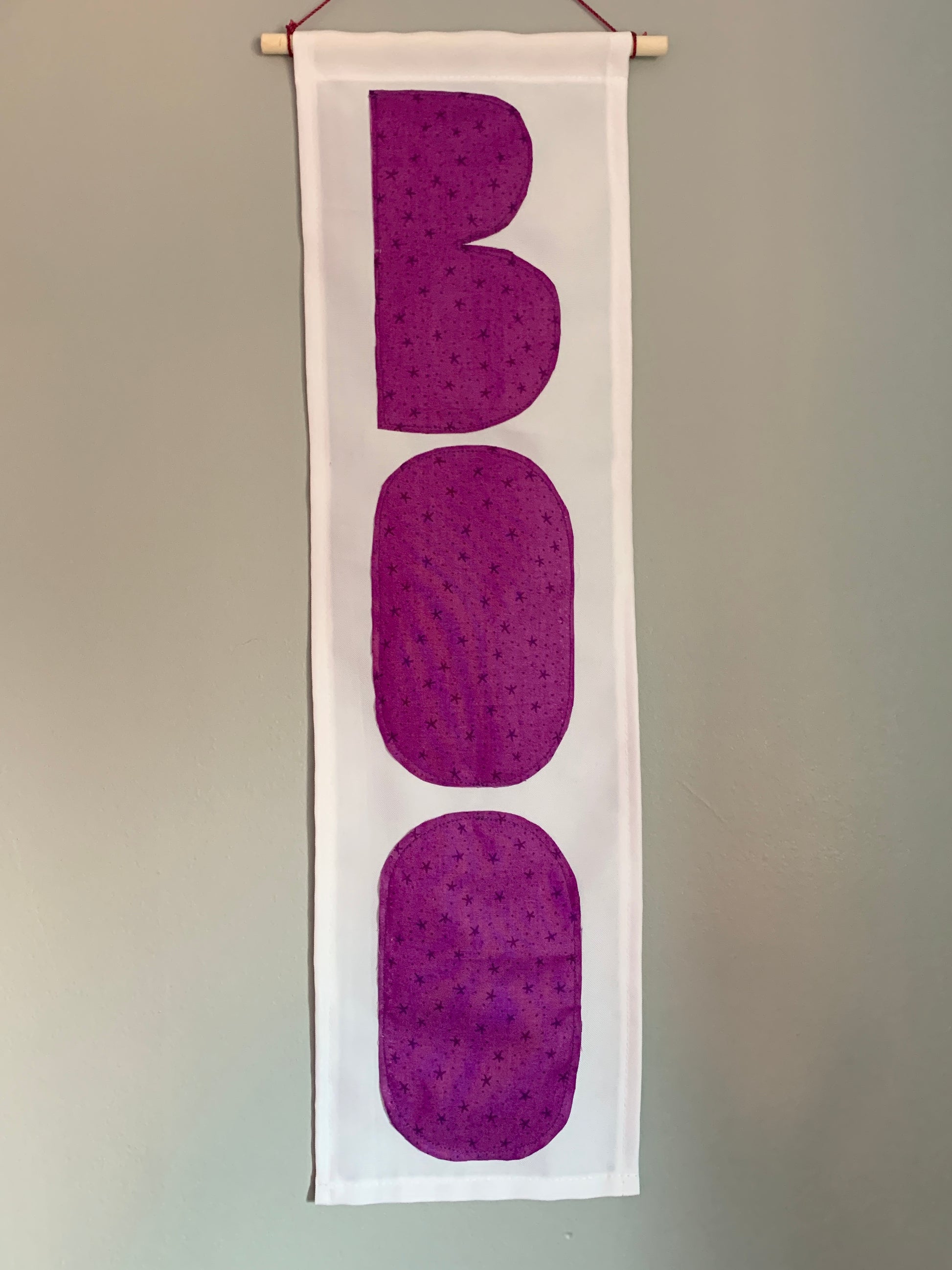 White banner with the word BOO in purple fabric