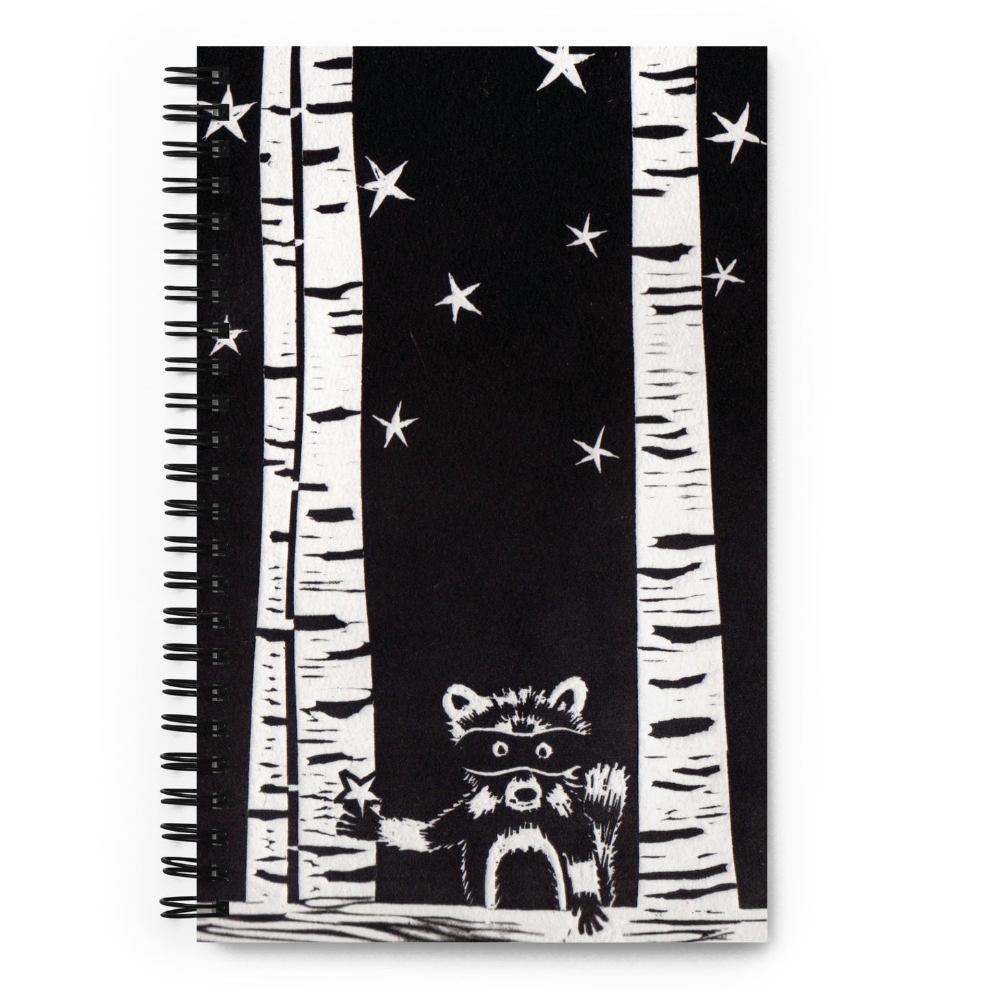 A notebook with a black and white image of a raccoon, trees and stars