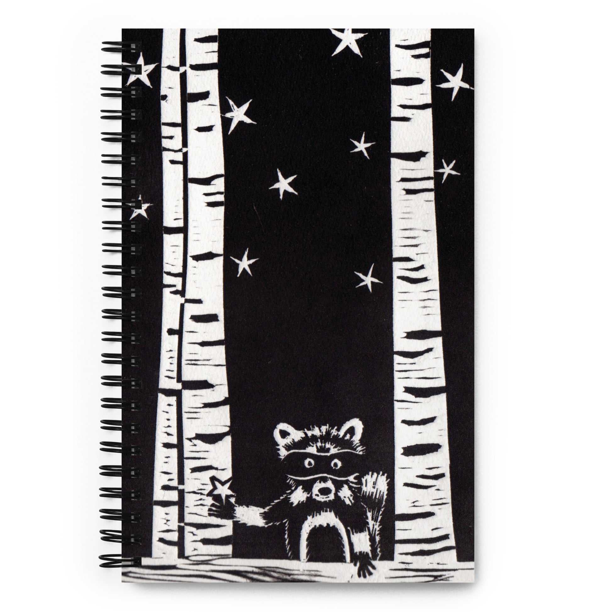 A notebook with a black and white image of a raccoon, trees and stars