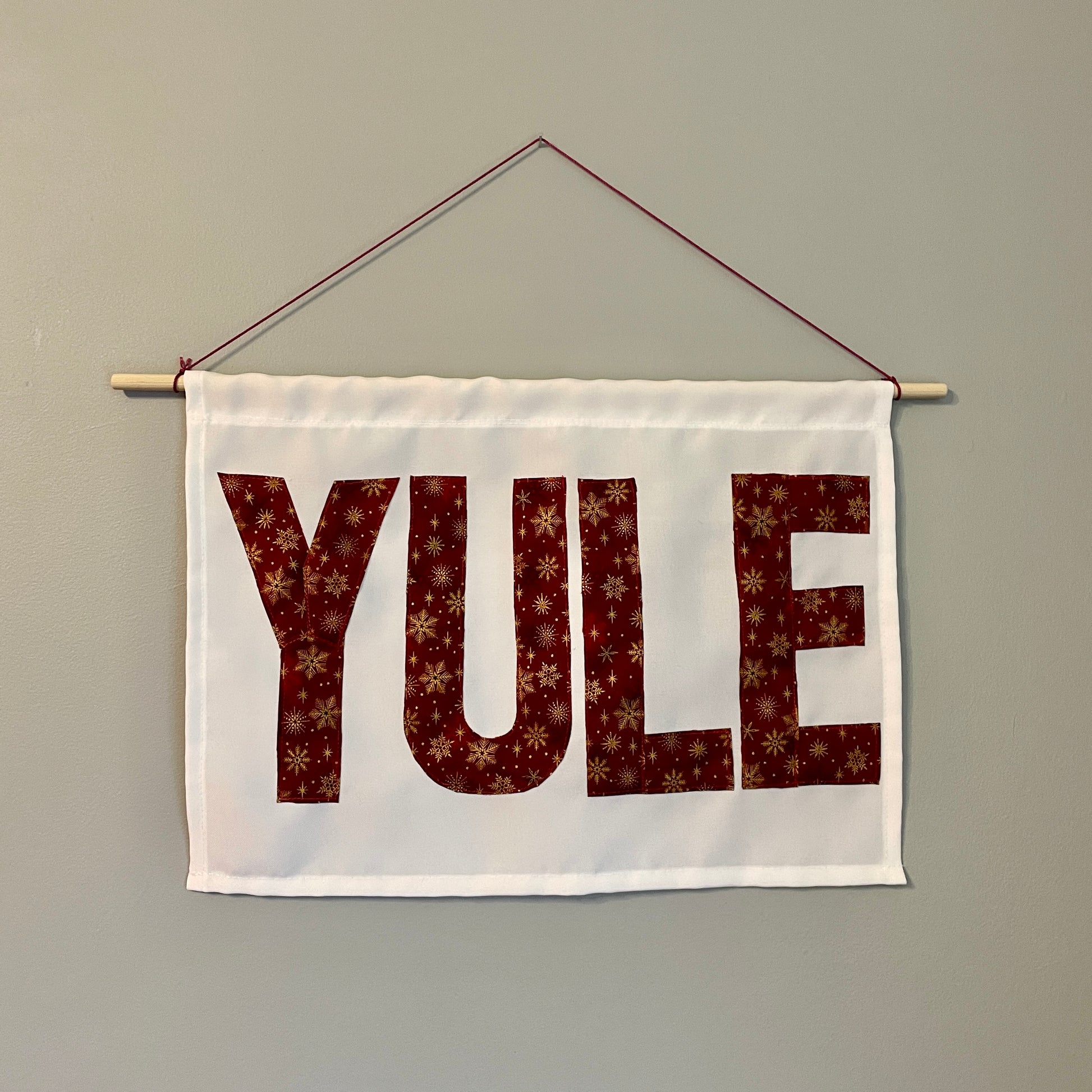 White banner with the word YULE in red fabric