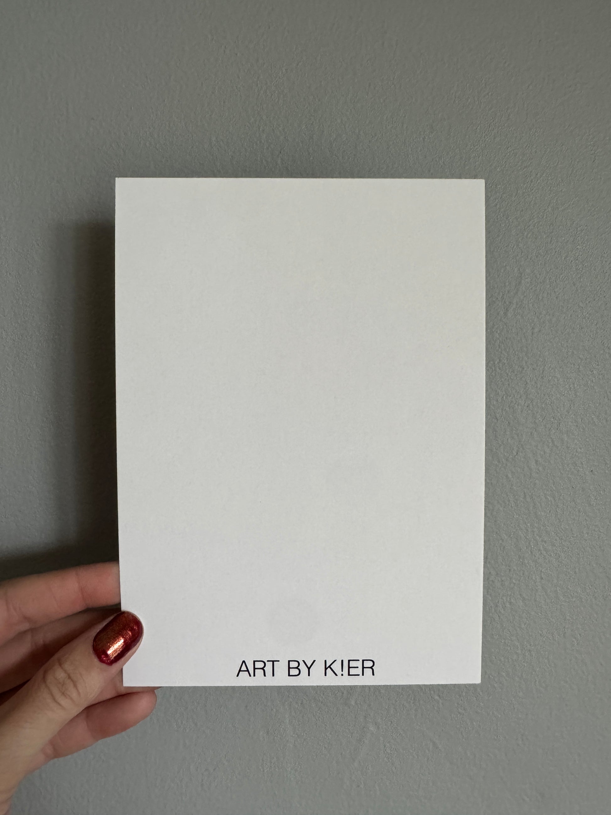 White card with 'Art by Kier' text held against a gray background