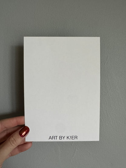 White card with 'Art by Kier' text held against a gray background