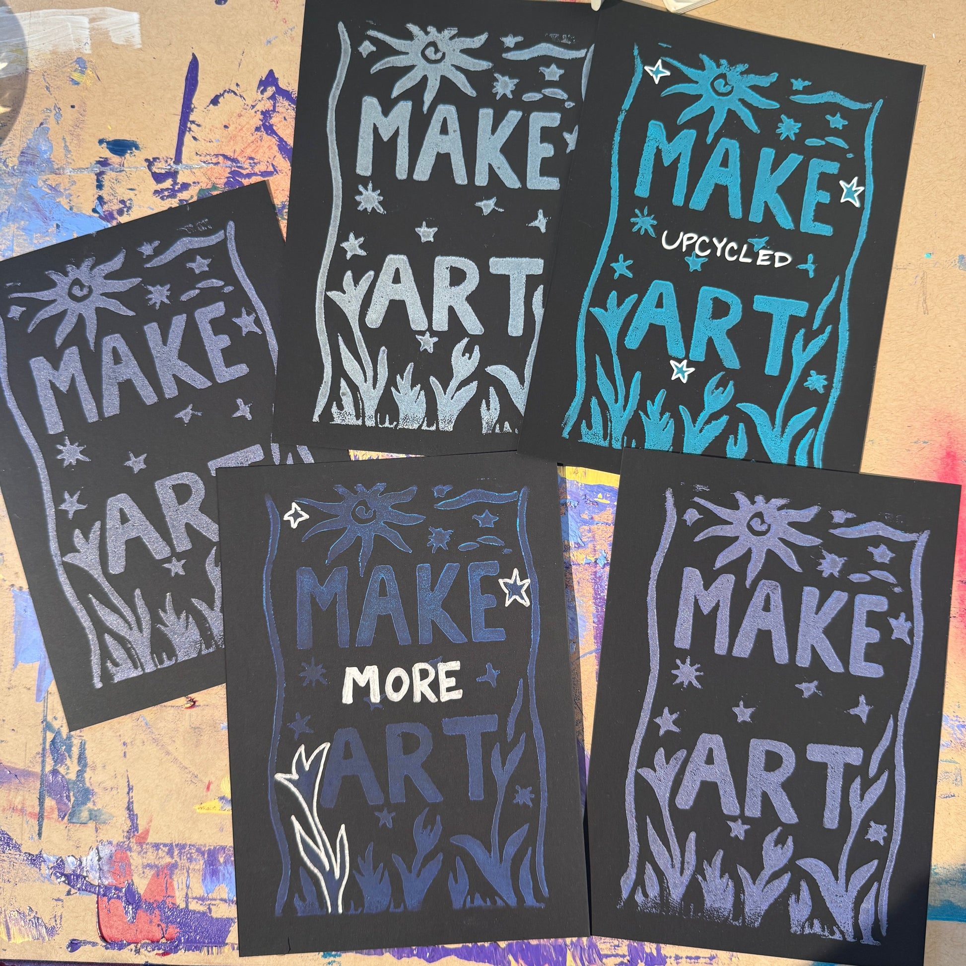Multiple black cards with purple and silver text reading "Make Art"