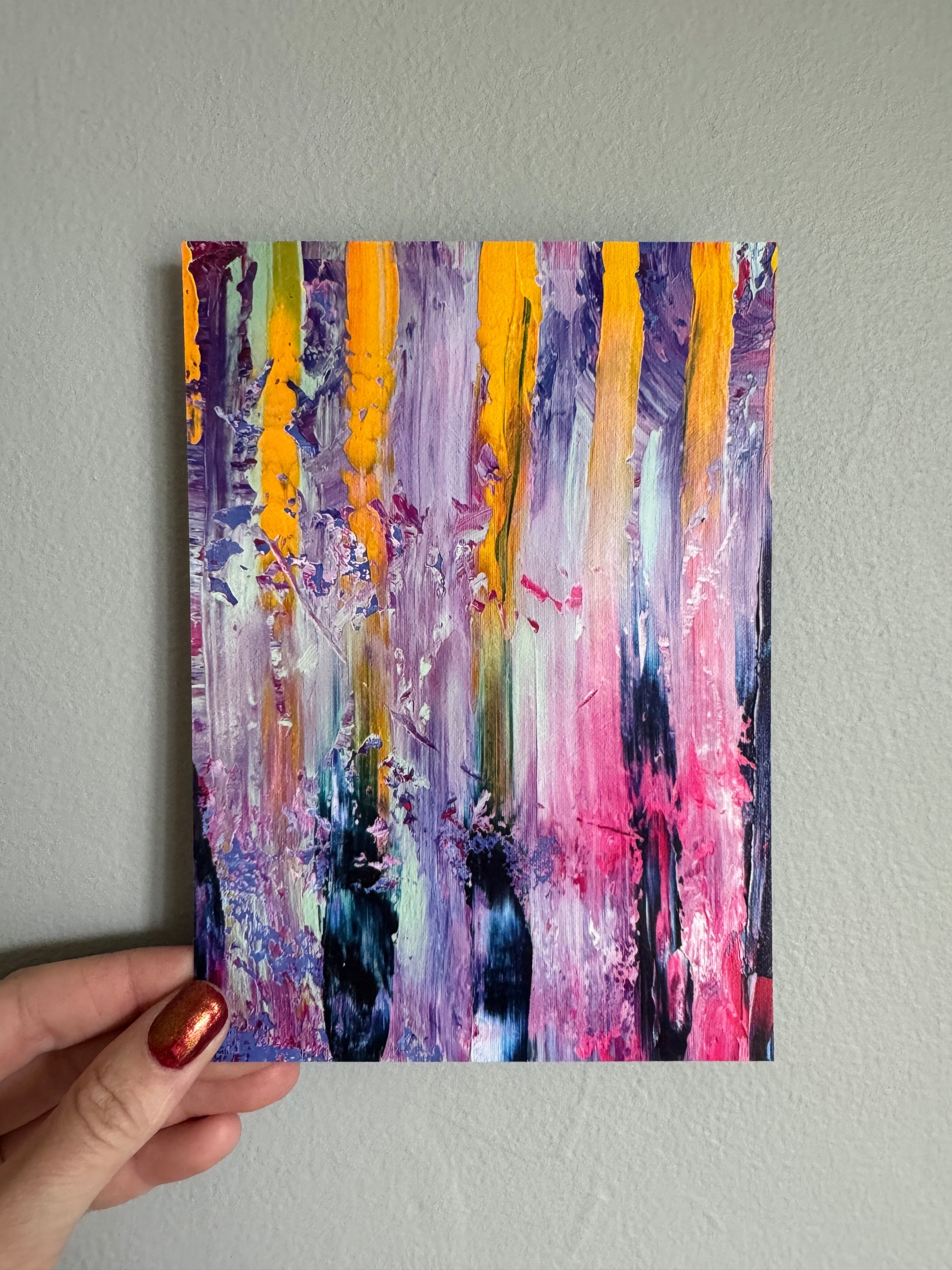 Abstract painting held by a hand against a plain background