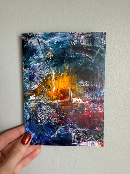 Abstract painting held by a hand against a light gray wall