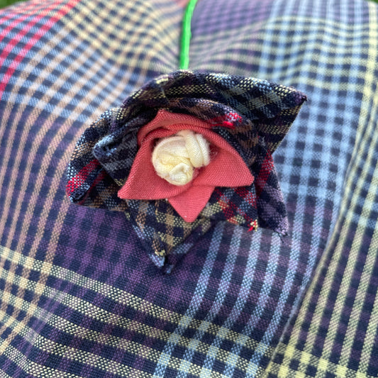 A fabric flower sits on top of a larger piece of the material it was made of. 