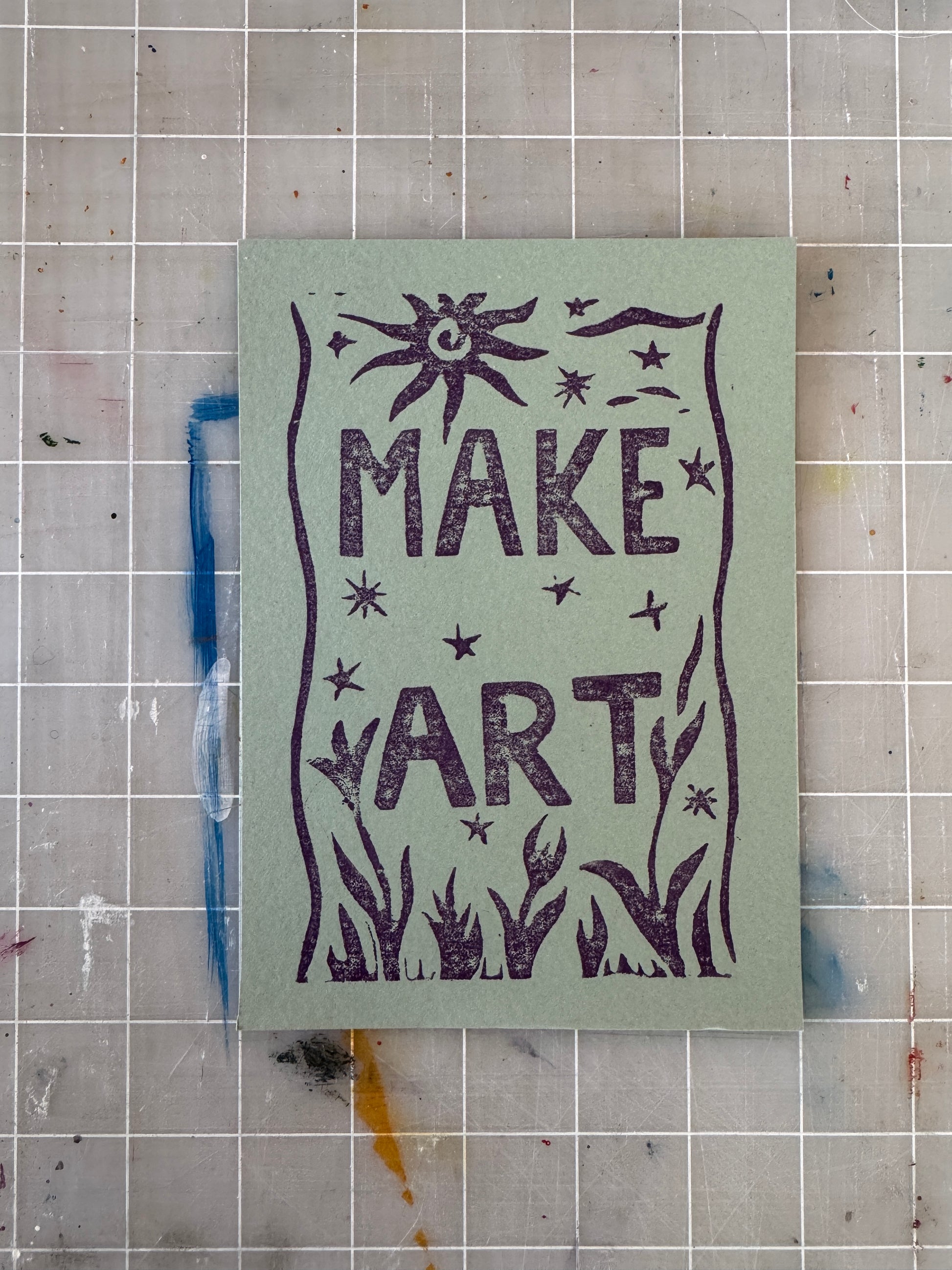 Green card with text reading "Make Art" on a grid background