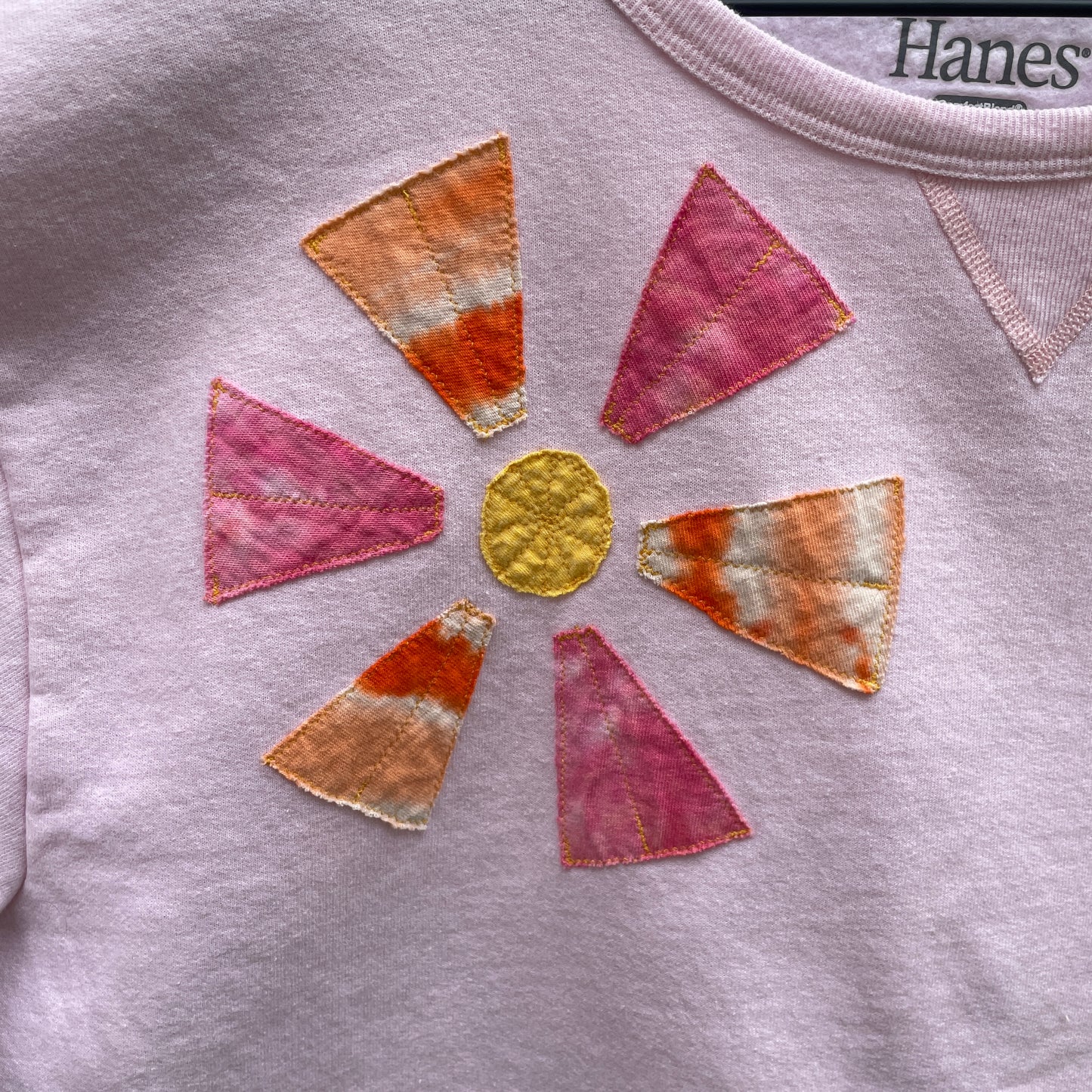 A light pink sweatshirt with applique orange and pink flowers