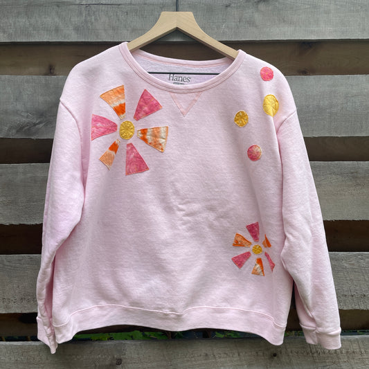 A light pink sweatshirt with applique orange and pink flowers