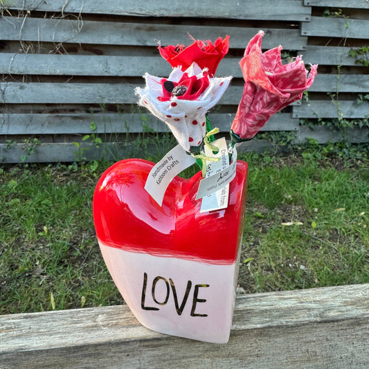Colorful flowers in a heart-shaped container with  'LOVE' text.