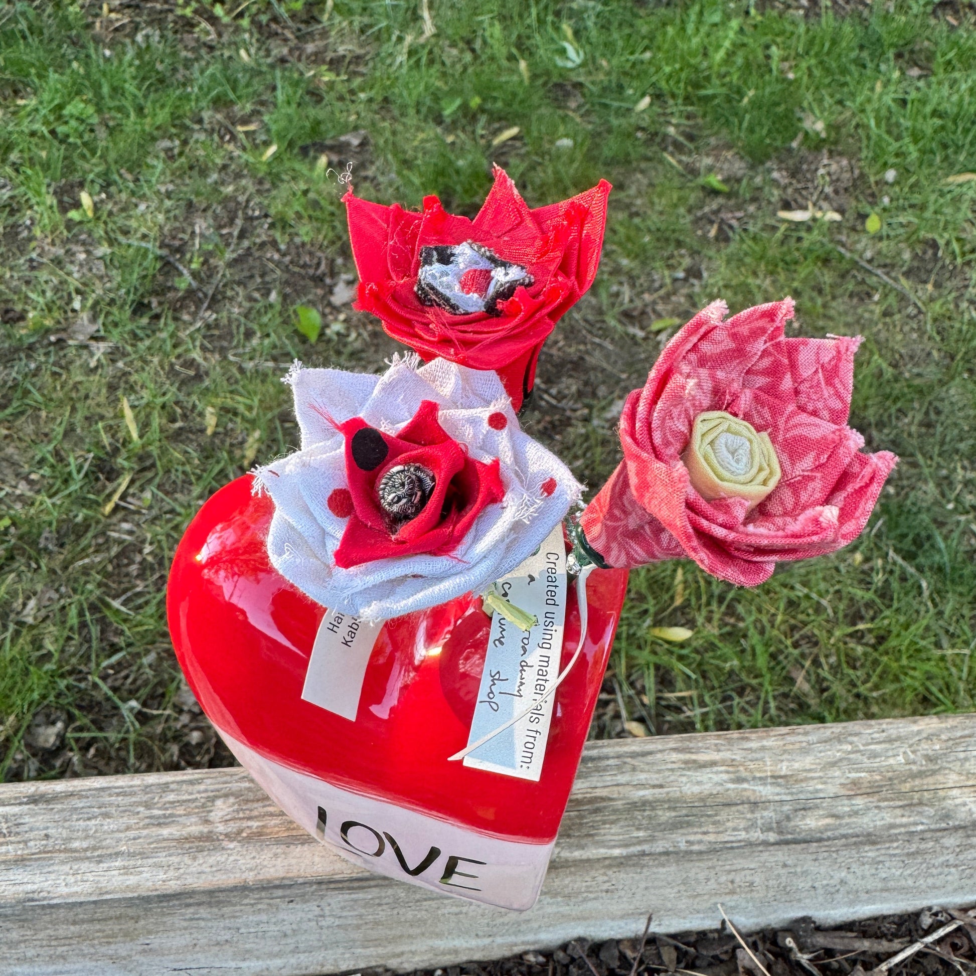 Colorful fabric flowers arranged in heart shaped vase