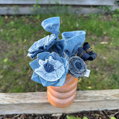 Blue fabric flowers in a brown vase against a blurred natural background