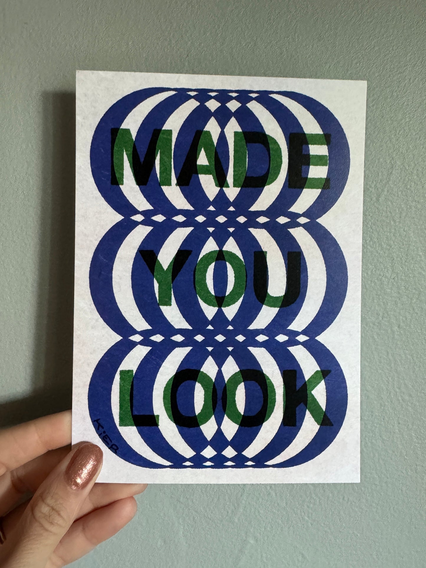 Hand holding a card with a geometric design on a plain background