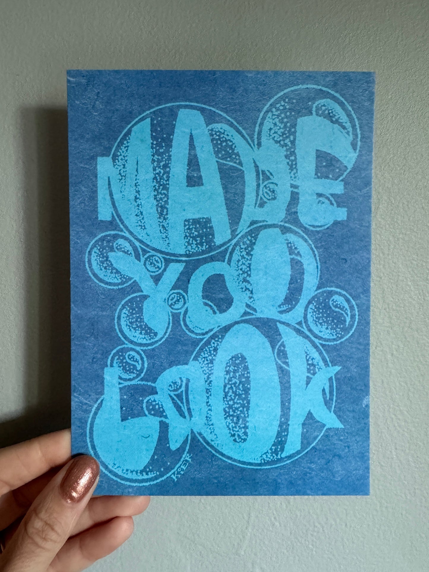 Blue card with decorative design held by a hand against a light gray background