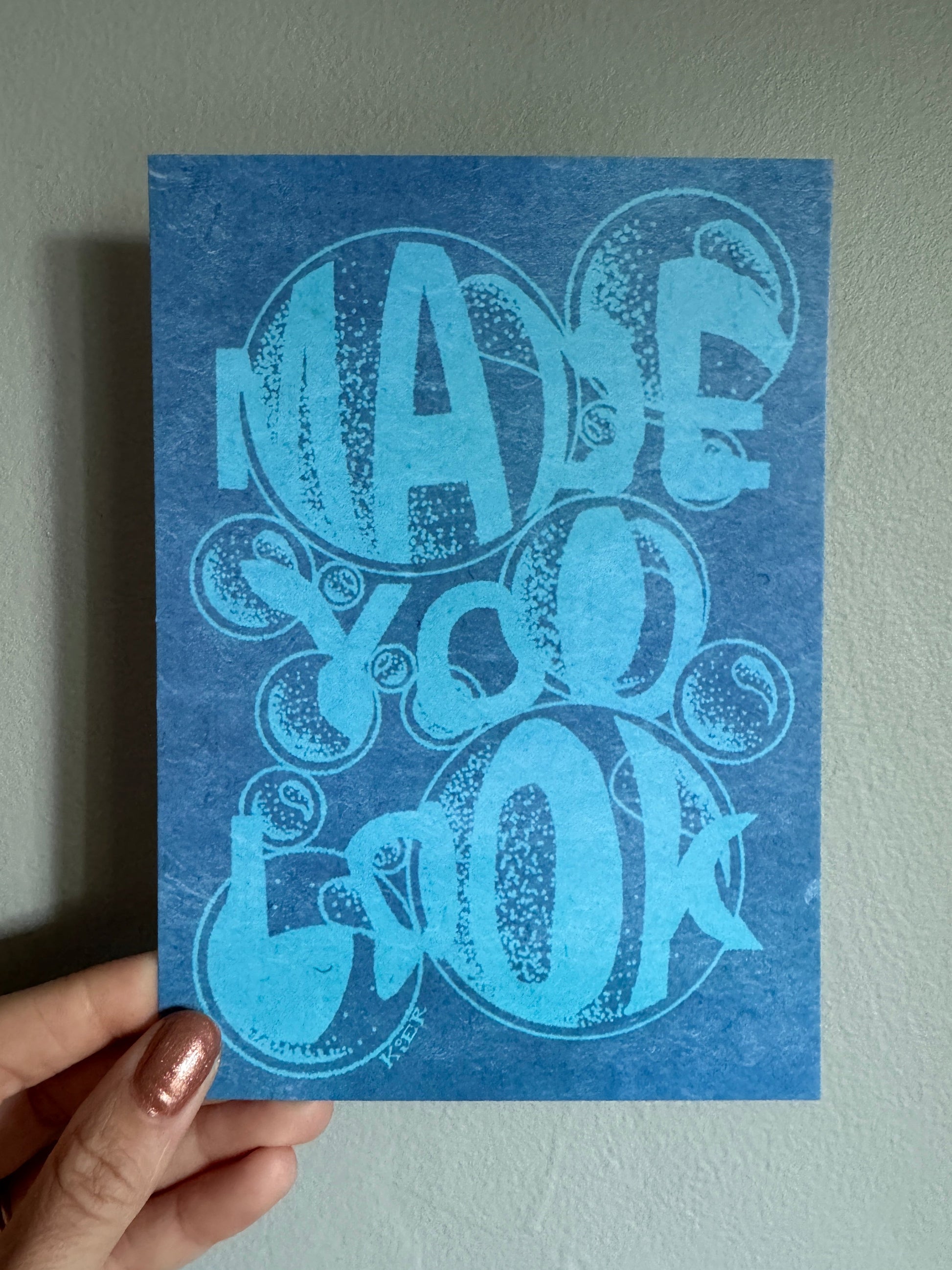 Blue card with decorative design held by a hand against a light gray background