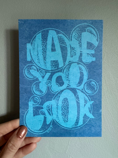 Blue card with decorative design held by a hand against a light gray background