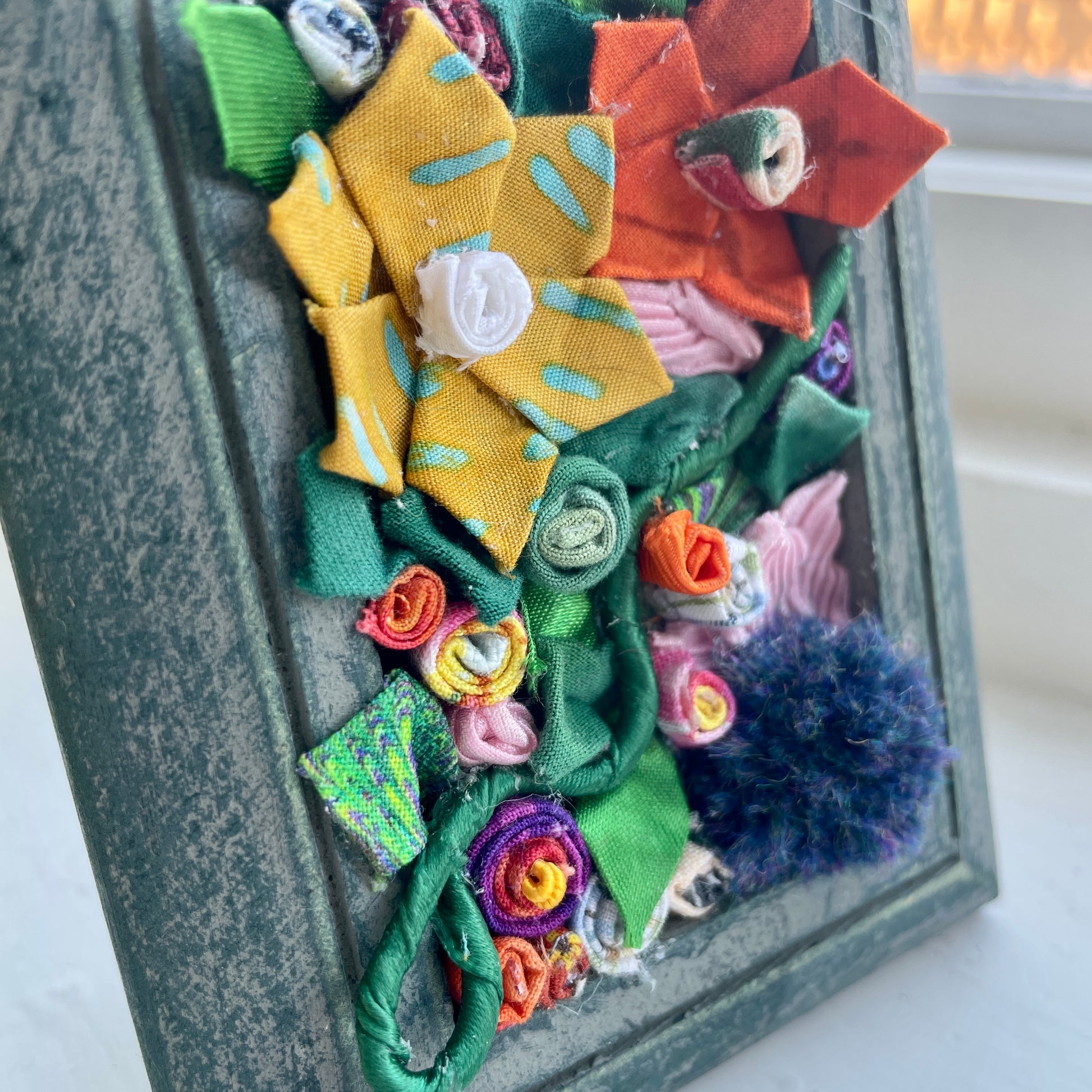 Blue picture frame with three dimensional flowers inside