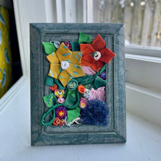 Blue picture frame with three dimensional flowers inside