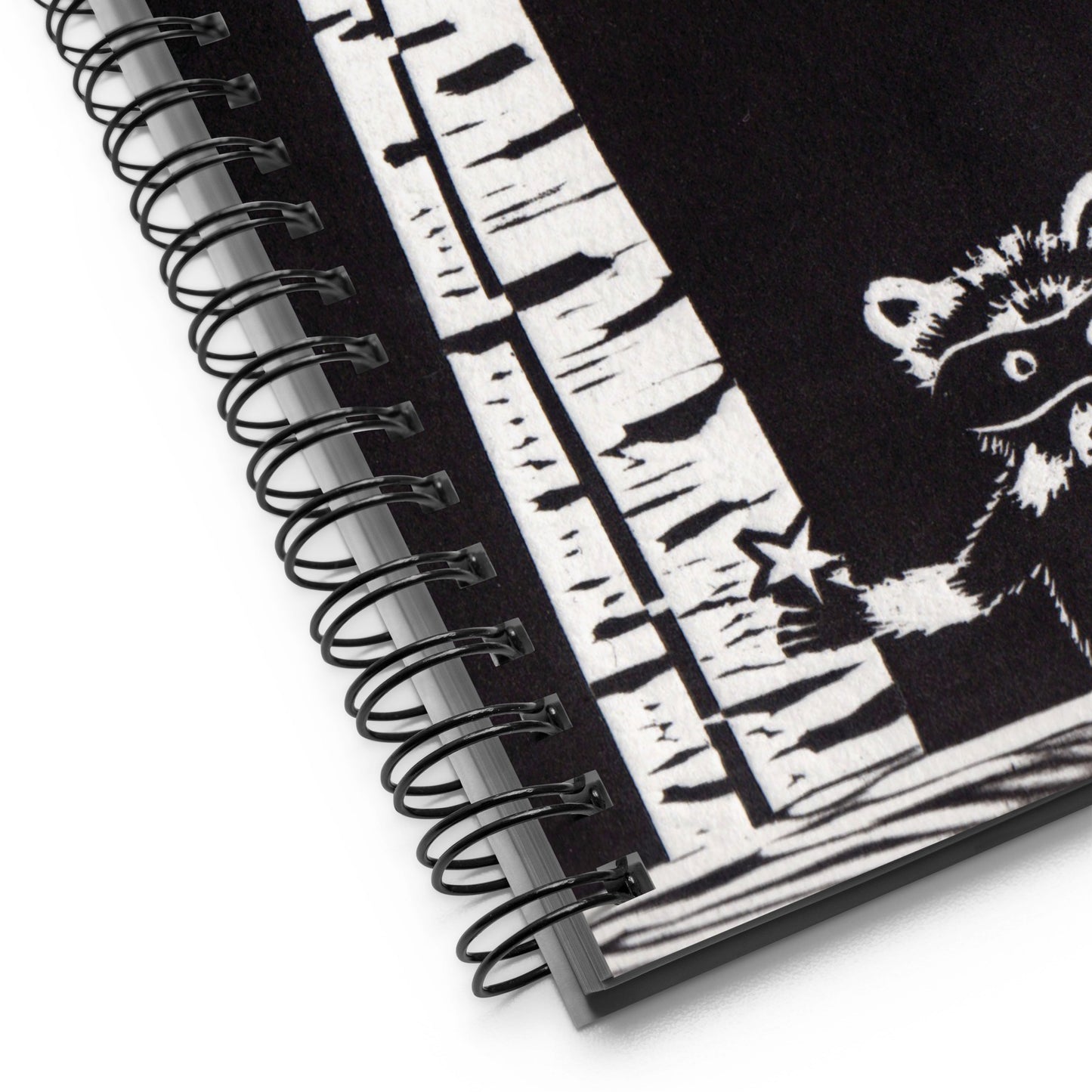A notebook with a black and white image of a raccoon, trees and stars