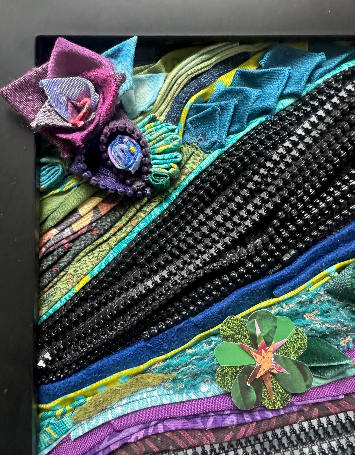 Colorful textile art piece with floral elements and black zippers